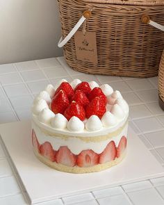 there is a cake with strawberries on it and a wicker basket behind it