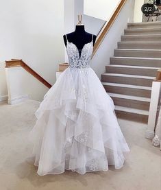 a white wedding dress on display in front of stairs