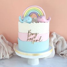 a baby shower cake with an elephant and rainbow decoration on the top that says boy girl