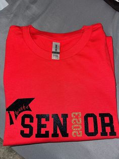 Senior 2024 T shirt. Design is 11 inches in width  Other T shirt colors available per school colors  *please note, darker T Shirt colors (Black, Navy) will be switched vinyl colors. Grad cap and words will be white instead of black, 2023 will remain gold glitter or if solid chosen, will be switched to another color such as red. message for specific color requests **any personalized orders are non-refundable and non-returnable Senior Shirts, Grad Cap, Red Shirt, School Colors, Red And Grey, Vinyl Colors, Colorful Shirts, Gender Neutral, Graphic Tees