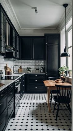 a kitchen with black cabinets and white tile flooring is seen from the doorway to the dining room