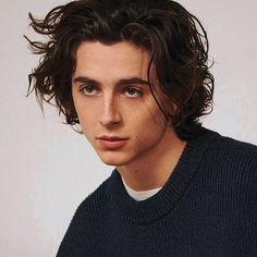 a close up of a person wearing a sweater and looking at the camera with a serious look on his face