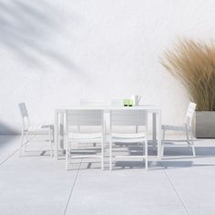 a white table and chairs sitting on top of a cement floor next to a potted plant