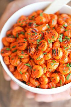 a person holding a white bowl filled with carrots