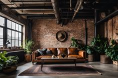 an industrial living room with brick walls and leather couches, potted plants, and large windows