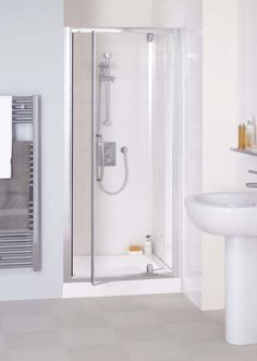 a bathroom with a sink, toilet and shower stall in white tile flooring next to a wall mounted radiator