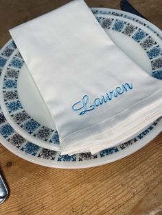 a personalized napkin on top of a blue and white plate with a silver fork