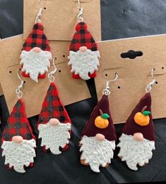 four christmas gnome earrings are sitting on a table