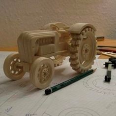 a wooden toy tractor sitting on top of a table next to markers and pencils