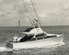 two men on a sailboat in the middle of the ocean, one holding a fishing rod