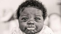 a black and white photo of a baby with an angry look on its face,