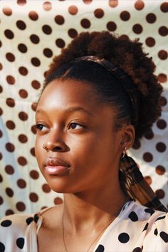 a close up of a person with a polka dot shirt and hair in a bun