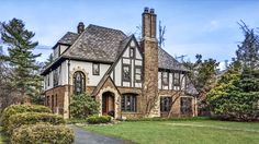 a large brick and stone house in the middle of a green yard with trees on both sides