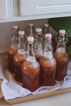 six bottles filled with liquid sitting on top of a wooden tray