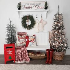 a white bench with christmas decorations and stockings hanging on the wall next to a tree