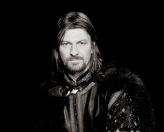 a man with long hair and beard wearing a leather jacket in front of a black background