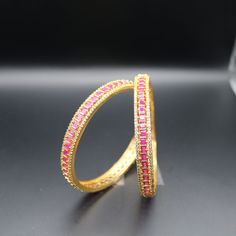 Gorgeous  gold plated matte bangle with CZ stones. Stylish and fashionable bangles are a perfect gift for any occasion. Whether you are looking for a thoughtful present for Mother's Day, a birthday gift for your special someone, or a way to celebrate an anniversary, a bangle is a surefire way to show your love and appreciation. Features: Gold Plated Pink , Green, whiteb CZ Stones Lightweight and elegant Can be paired with any dress, kurti, or saree Material:  Gold Plated Brass CZ Stones Pink,Green, White Variations: 1. Medium Stone Bangles- SOLD as 4 Bangles-      2 Bangles -PinkColor-  Size 2-8      2 Bangles -Green Color -  Size 2-6       2. Small Stone Bangles-8bangles(2 Sets-Each 4)     4 Pink+ 4 Green(Size 2-6) - SOLD as 8 Bangles Ready to ship from California Free US standard shippin Pink Hand Set Bangle As A Gift, Pink Stackable Bangle For Party, Stackable Pink Bangle For Parties, Pink Stackable Wedding Bangle, Elegant Pink Bangle For Festivals, Green Temple Jewelry Bangle, Yellow And Pink Bangles Set, Pink And Green Bangles Set, Traditional Adjustable Pink Bangle