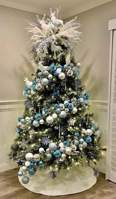 a decorated christmas tree with blue and silver ornaments on it's base in a room