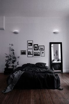 a bed sitting on top of a hard wood floor next to a wall filled with pictures