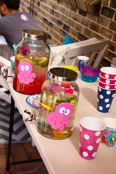 there are many cups and jars sitting on the table with one person in the background