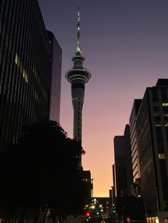 the sky tower is lit up at night in this cityscape photo taken from an empty street