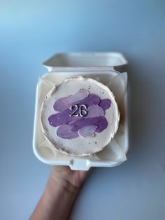 a person holding up a cake with the number twenty on it in a plastic container