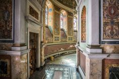 the interior of an old church with stained glass windows and marble flooring, along with ornate paintings on the walls