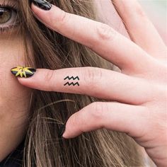 a woman with black and yellow nail art on her fingers holding up her hand to her face