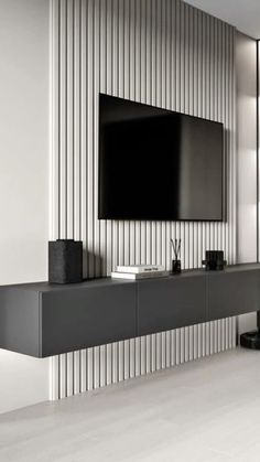 an entertainment center with a flat screen tv mounted on it's side, in front of a striped wall