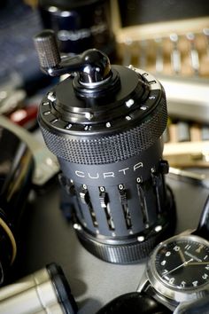 a camera lens sitting on top of a table next to some other cameras and watches