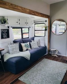 a living room with a couch, mirror and rug in front of the couch is made out of wood