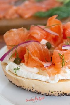 a bagel with cream cheese, salmon and capers on it sitting on a plate