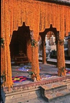 an outdoor area with orange drapes and rugs on the ground in front of it