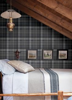 a bed sitting under a wooden ceiling next to a wall with pictures hanging on it