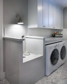 a washer and dryer in a white laundry room with cabinets on the wall