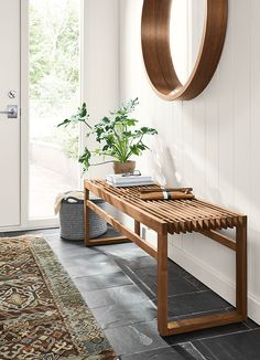 a wooden bench sitting in front of a door next to a rug and potted plant