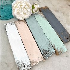 several different colored wood planks sitting next to a white flower