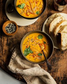 two bowls of soup with bread on the side