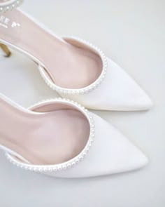 a pair of white high heels with pearls on the toe and heel are sitting next to each other