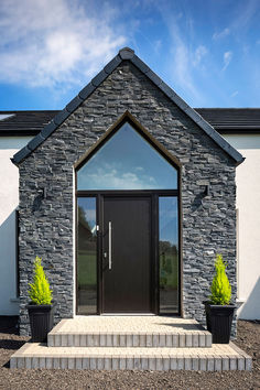 a black front door with two planters on the steps