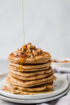 a stack of pancakes with syrup being poured on top