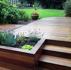 a wooden deck surrounded by plants and flowers