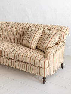 a striped couch sitting on top of a hard wood floor next to a white wall