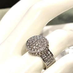 a diamond ring on top of a white cloth covered table with an object in the background