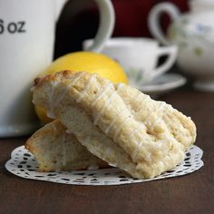 two lemon shortbreads sitting on a doily next to a cup and saucer