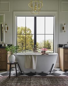 a bathroom with a checkered floor, large windows and a claw foot bathtub