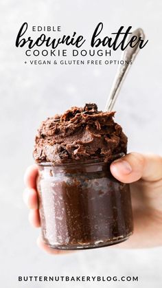 a hand holding a jar filled with brownie batter and topped with chocolate frosting