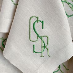 the monogrammed napkins are embroidered with green thread on white linen, which is rolled up in half