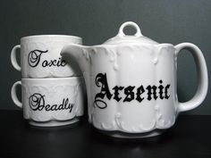 two white teapots sitting next to each other on top of a black table