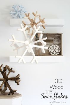 some snowflakes are hanging on the wall in front of a white shelf with an ornament